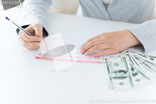 Image of close up of hands with lottery ticket and money