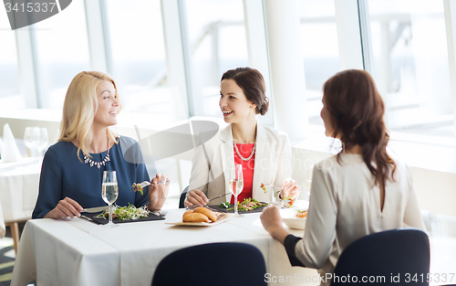 Image of happy women eating and talking at restaurant
