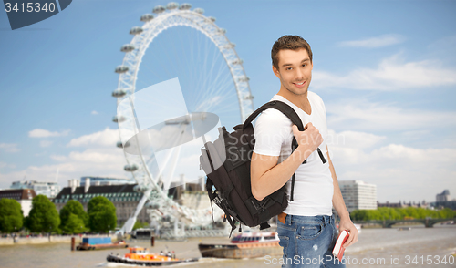 Image of happy young man with backpack and book travelling