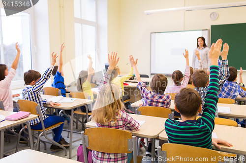 Image of group of school kids raising hands in classroom