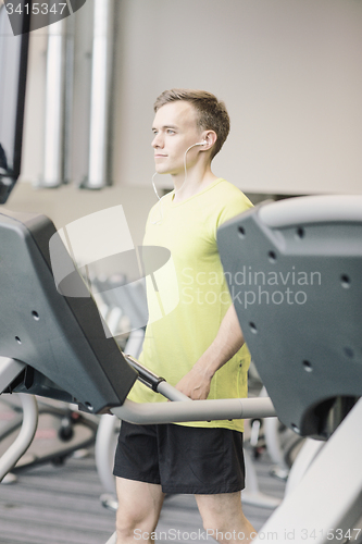Image of man with smartphone exercising on treadmill in gym