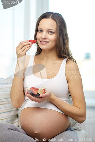 Image of happy pregnant woman eating fruits at home