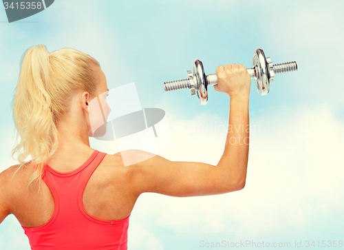 Image of sporty woman with heavy steel dumbbell from back