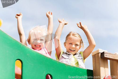 Image of happy girls waving hands on children playground