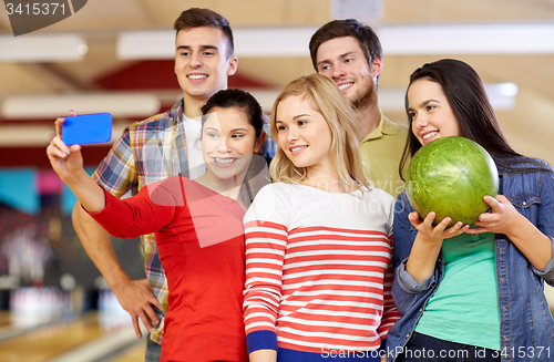 Image of happy friends with smartphone in bowling club