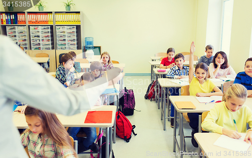 Image of group of school kids raising hands in classroom