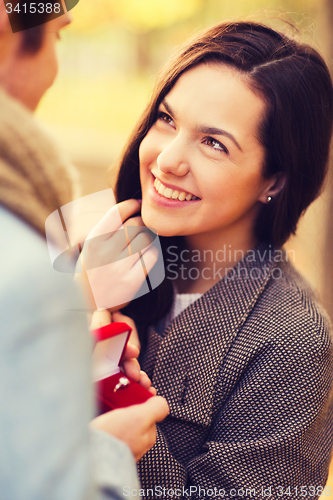 Image of close up of smiling couple with gift box in park