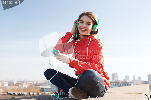 Image of happy young woman with smartphone and headphones