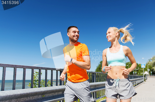 Image of smiling couple running at summer seaside