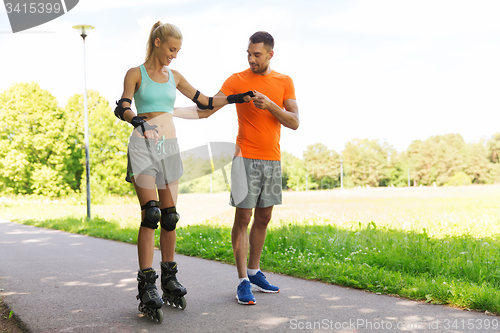 Image of happy couple with roller skates riding outdoors