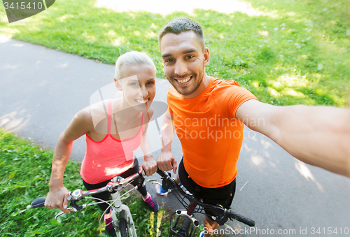 Image of couple with bicycle taking selfie outdoors