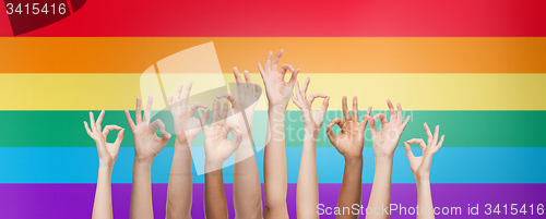 Image of hands showing ok sign over rainbow background