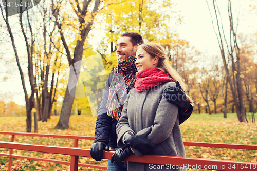 Image of smiling couple hugging on bridge in autumn park