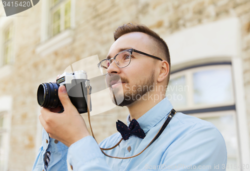 Image of young hipster man with film camera in city