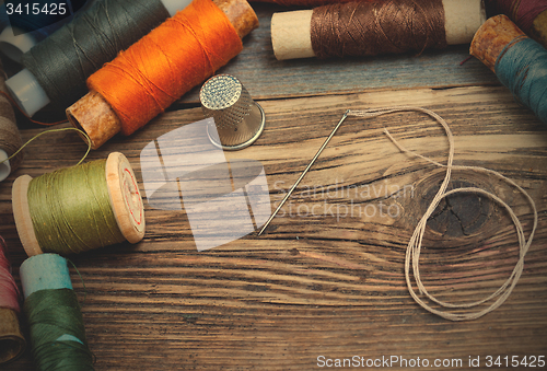 Image of spool of thread, a thimble and a sewing needle