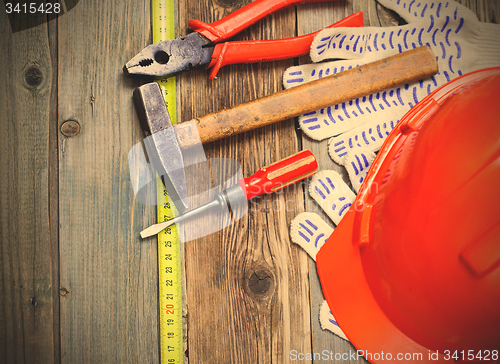 Image of Vintage hammer, pliers, screwdriver, tape measure, a bright helm