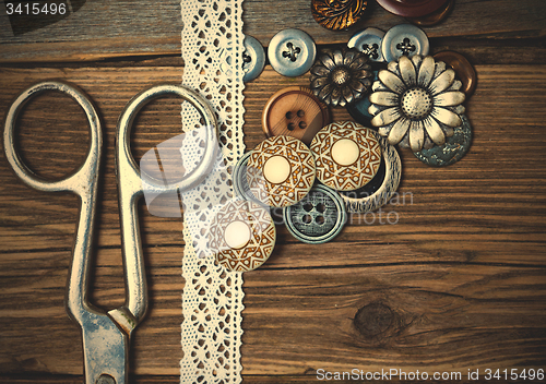 Image of several vintage buttons, lace, and a dressmaker scissors