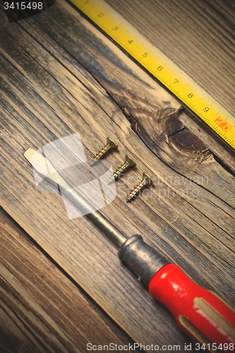 Image of screws, screwdriver and old yellow measuring tape 