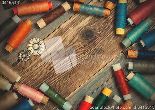 Image of two old buttons and vintage reels of varicolored thread