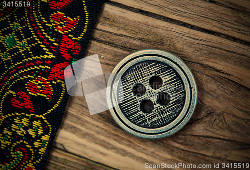 Image of old band with embroidered ornaments and vintage button