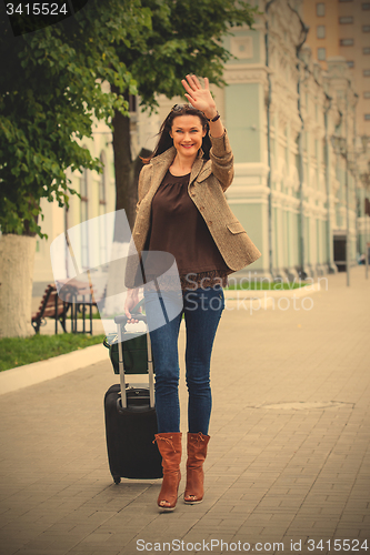 Image of adult beautiful businesswoman with a suitcase walking along the 