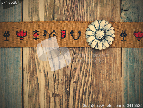 Image of vintage band with embroidered ornaments and old button flower