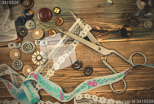 Image of buttons, lace, tape and a dressmaker scissors