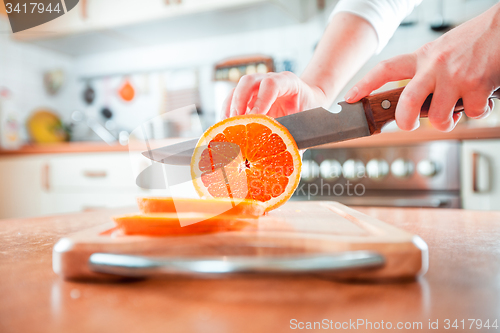 Image of Woman\'s hands cutting orange