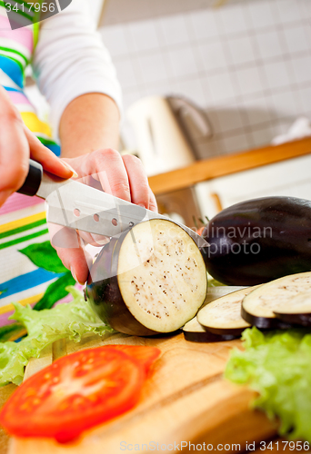 Image of Woman\'s hands cutting aubergine eggplant