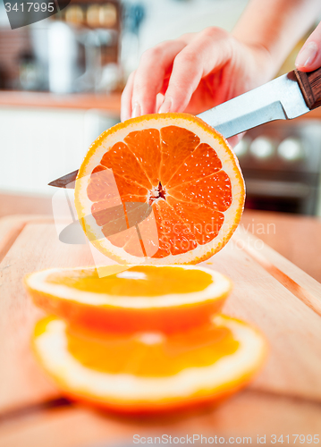 Image of Woman\'s hands cutting orange