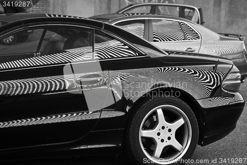 Image of Car and stripes, car parked in front of a building with striped 