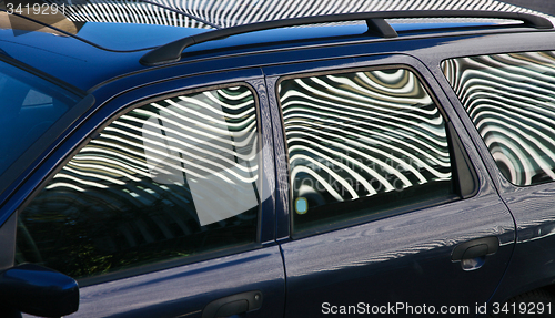 Image of Car and stripes, car parked in front of a building with striped 