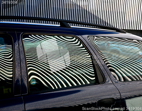 Image of Car and stripes, car parked in front of a building with striped 