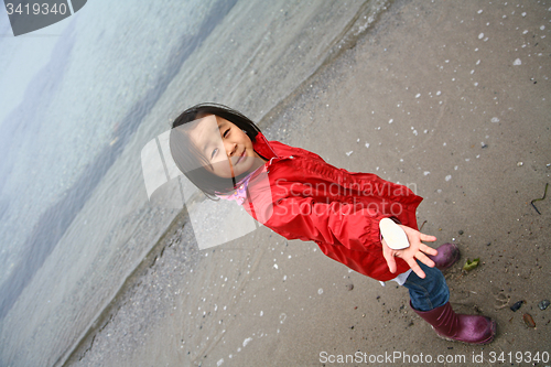 Image of Girl showing a stone on a beach