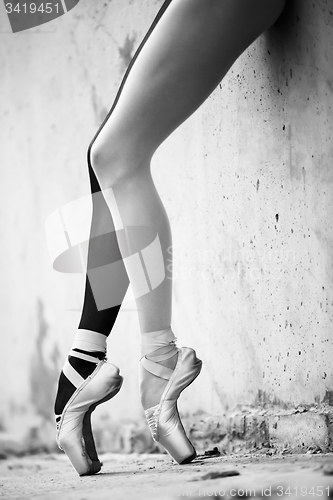 Image of Ballerina feet close-up on a background of textured concrete wal