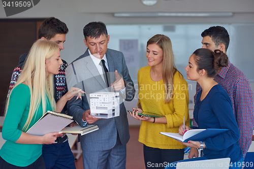 Image of group of students working with teacher on  house model