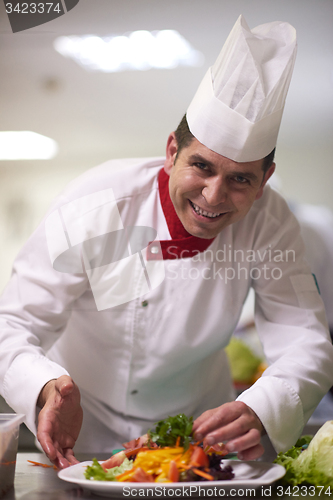 Image of chef in hotel kitchen preparing and decorating food