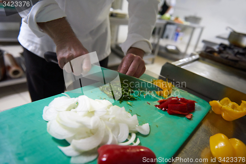 Image of chef in hotel kitchen  slice  vegetables with knife