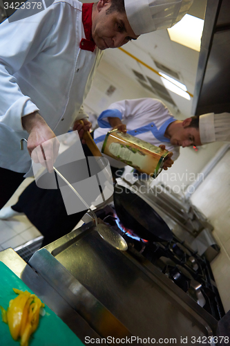 Image of chef in hotel kitchen prepare food with fire