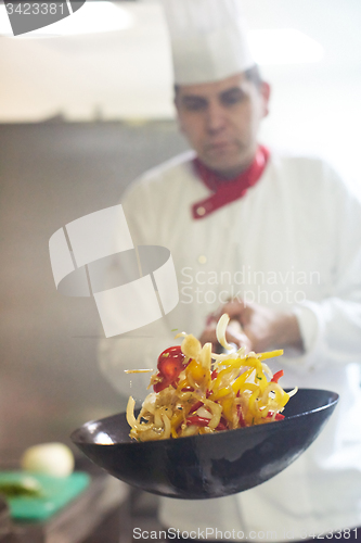 Image of chef in hotel kitchen prepare food with fire