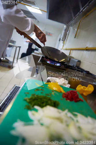 Image of chef in hotel kitchen prepare food with fire