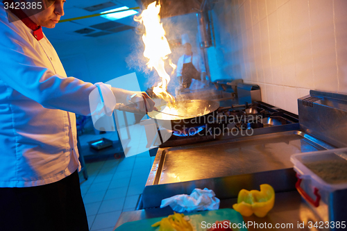 Image of chef in hotel kitchen prepare food with fire