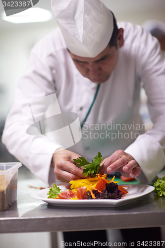 Image of chef in hotel kitchen preparing and decorating food