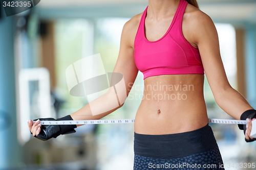 Image of young fit woman measuring belly