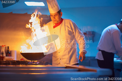 Image of chef in hotel kitchen prepare food with fire