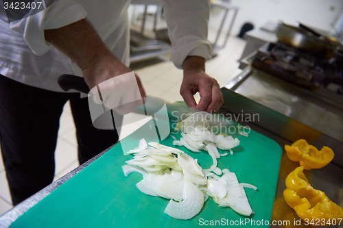 Image of chef in hotel kitchen  slice  vegetables with knife