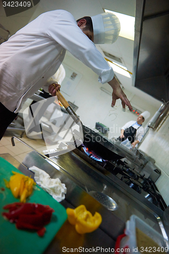 Image of chef in hotel kitchen prepare food with fire