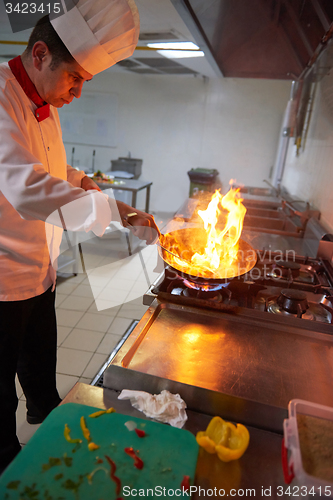 Image of chef in hotel kitchen prepare food with fire