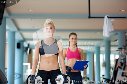 Image of young woman in fitness gym lifting  weights