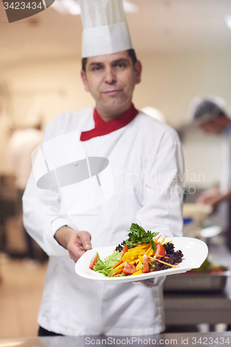 Image of chef in hotel kitchen preparing and decorating food